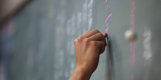 A teacher writes on a chalkboard during a class at the Korean High School in Tokyo, Japan, on Thursday, Sept. 25, 2014. The school in Tokyos Kita ward looks much like any such Japanese institution with a large clock sitting atop of gray buildings. Inside, all notices are written in Korean and female students and teachers wear the traditional chima jeogori, a full skirt and short jacket. Photographer: Tomohiro Ohsumi/Bloomberg via Getty Images 