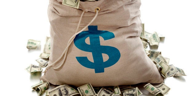 Canvas money bag with dollar symbol is overflowing with dollar bills