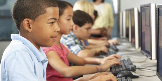 Elementary Students Working At Computers In Classroom Using Keyboard Concentrating