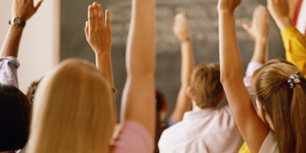 Students raising hands in classroom, rear view