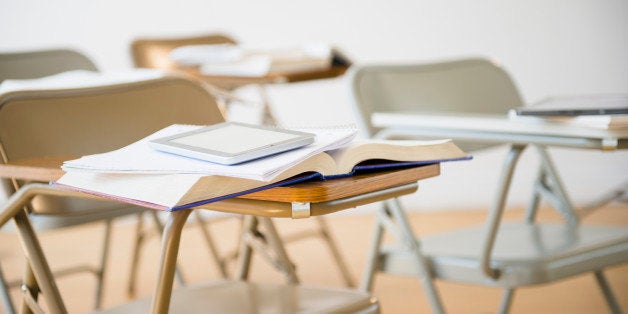 Digital tablet and book on desk in classroom