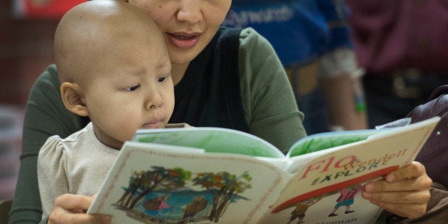 WASHINGTON, DC - JANUARY 29: Five-year-old Ayana Ruslan and her mother Altinay Kuchukeeva read a book by photographer and artist William Wegman (NP) at the Georgetown Lombardi Comprehensive Cancer Center in Washington, DC on January 29, 2015. Wegman (famous for his shots of Weimaraner dogs in dress and funny situations; lately author of children's books) visited the pediatric oncology center to read his latest book 'Flo and Wendell Explore' for kids, and he is donating five photos to the hospital. Twenty two additional photos will be sold with all proceeds going to the hospital. The Lombardi Center is exhibiting his work in the atrium. (Photo by Linda Davidson / The Washington Post via Getty Images)