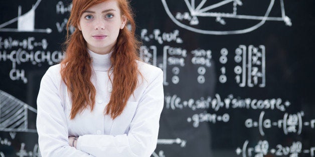 close-up of schoolgirl succesful looking in the camera in a chemistry lab with a blackboard on the background