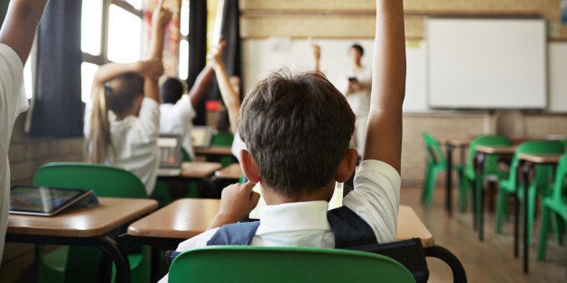 School children in uniforms in class with tablets