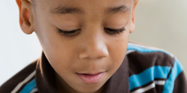 African American boy reading book on sofa