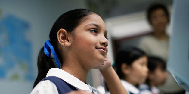 Girl at computer in classroom with other students in background