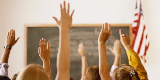 Students raising hands in classroom, rear view