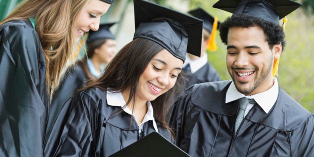 Happy group of friends looking at diplomas after graduating