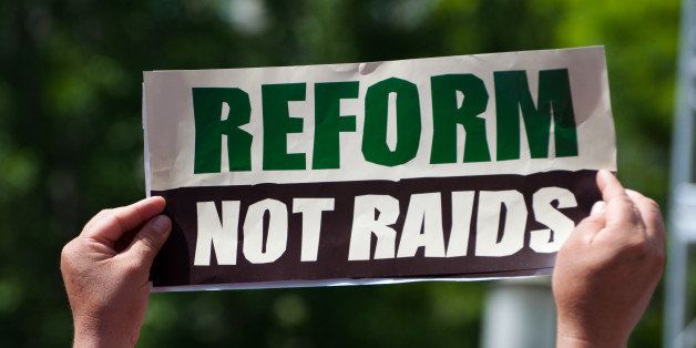 Immigration reform activists protest with a sign reading 'Reform Not Raids.'