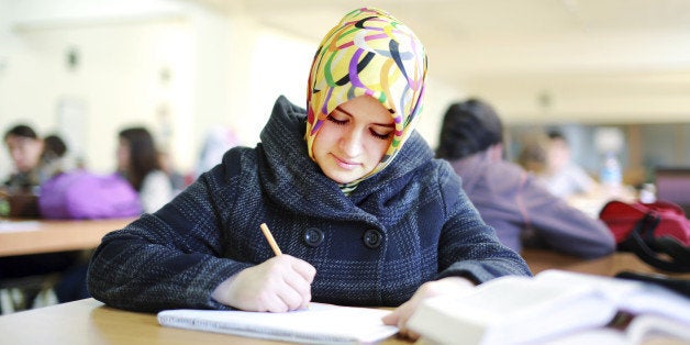 Muslim female student reading book in library