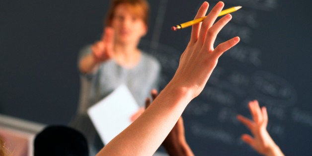 Teacher pointing to raised hands in classroom