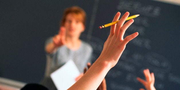 Teacher pointing to raised hands in classroom