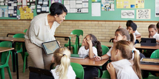 School children in uniforms in class with tablets