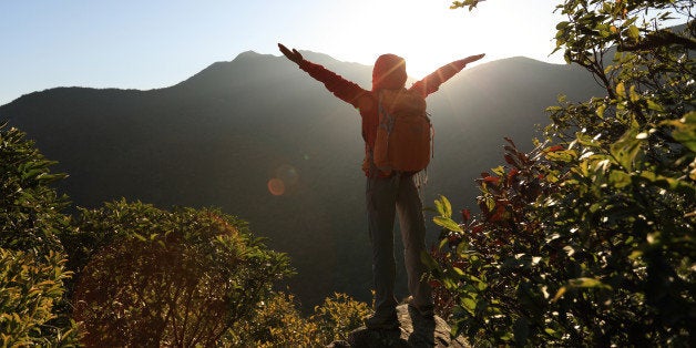 successful woman hiker open arms on sunrise mountain peak