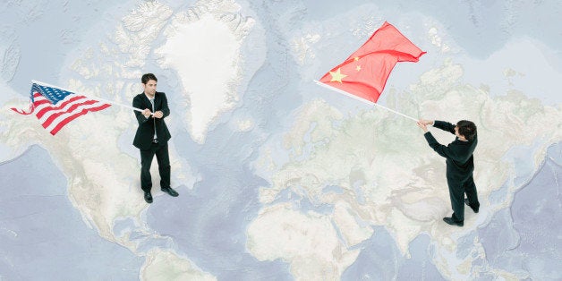 Businessmen standing on world map, waving American and Chinese flags