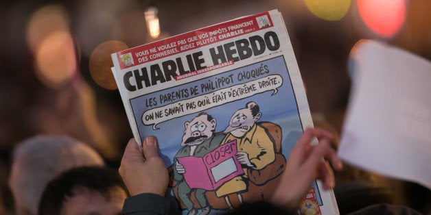 PARIS, FRANCE - JANUARY 07: A person holds an issue of 'Charlie Hebdo' as crowds gather at 'Place de la Republique' during a