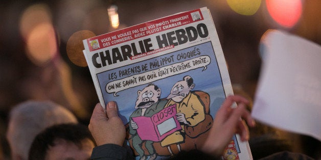 PARIS, FRANCE - JANUARY 07: A person holds an issue of 'Charlie Hebdo' as crowds gather at 'Place de la Republique' during a vigil following the terrorist attack earlier today on January 7, 2015 in Paris, France. Twelve people were killed, including two police officers, as two gunmen opened fire at the offices of the French satirical publication Charlie Hebdo. (Photo by Marc Piasecki/Getty Images)