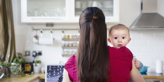 mother holding baby while working on computer