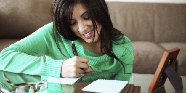 Woman writing note on coffee table