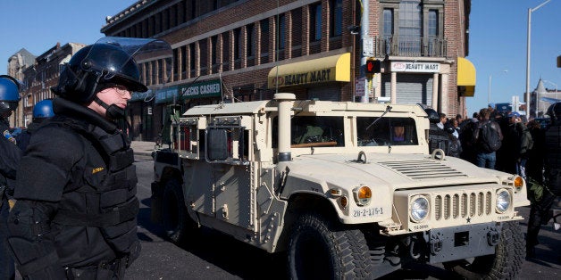 A National Guard vehicle drives by a Maryland State Trooper Tuesday, April 28, 2015, in the aftermath of rioting following Monday's funeral for Freddie Gray, who died in police custody. The violence that started in West Baltimore on Monday afternoon had spread to East Baltimore and neighborhoods close to downtown and near Camden Yards. (AP Photo/Matt Rourke)