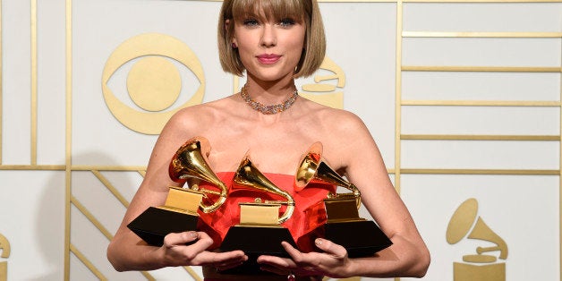 Taylor Swift poses in the press room with the awards for album of the year for 1989, pop vocal album for 1989 and best music