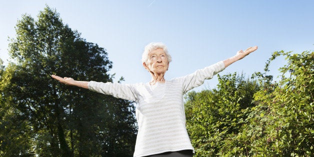 90 years old senior woman, making breathing exercise, with concentration outdoors at a wonder summer morning