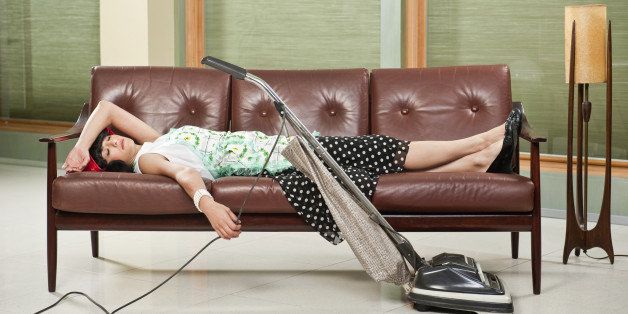 1950's housewife with apron, napping on mid-sentury modern couch with Retro Hoover vacume cleaner