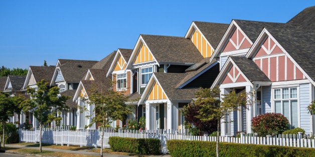 A row of a new houses in Richmond, British Columbia, Canada. Front yards of the houses and street with trees and bushes.