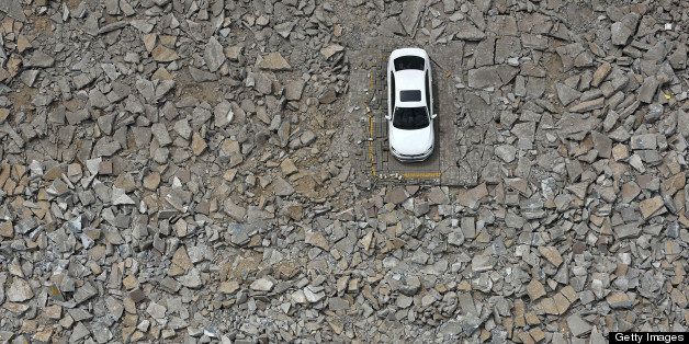 A car that was left behind in a shutdown carpark is surrounded by debris after construction began to widen a street in Taiyuan, north China's Shanxi province on May 6, 2013. The construction unit started working around the car for several days after they failed to contact the owner several days ago. CHINA OUT AFP PHOTO (Photo credit should read AFP/AFP/Getty Images)