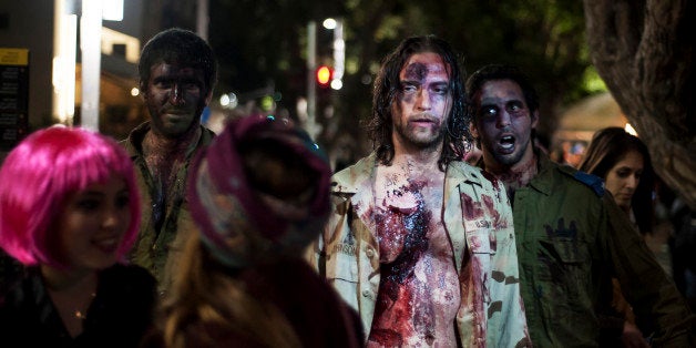 Israelis dressed as a zombies takes part in the customary 'Zombie Walk' in the city of Tel Aviv, on the eve of the Jewish holiday of Purim, late on March 15, 2014. The carnival-like Purim holiday is celebrated with parades and costume parties to commemorate the deliverance of the Jewish people from a plot to exterminate them in the ancient Persian empire 2,500 years ago, as described in the Book of Esther. AFP PHOTO/DAVID BUIMOVITCH (Photo credit should read DAVID BUIMOVITCH/AFP/Getty Images)