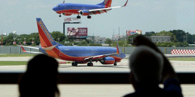 In this photo taken Friday, June 25, 2010 passengers traveling on Southwest Airlines watch as one plane waits to takeoff and another lands at Midway Airport in Chicago. Southwest Airlines Co. added an upbeat note to a strong quarter for the airline industry Thursday, July 29, 2010, by reporting a $112 million profit for spring and early summer. (AP Photo/Charles Rex Arbogast)