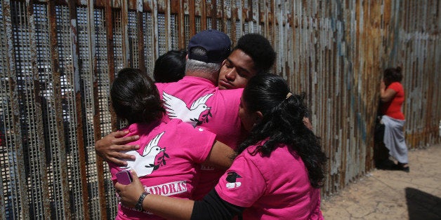 TIJUANA, MEXICO - MAY 01: Deported family members of 'Dreamers' and their supporters pray at the U.S.-Mexico border fence on
