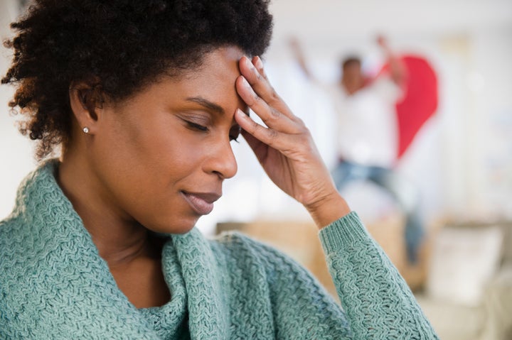 Black woman with headache and playful son in background