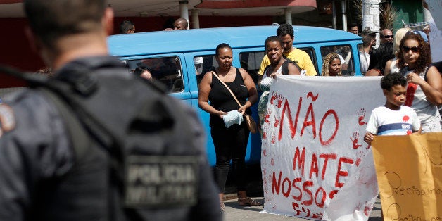 Protesters hold a sign with a handwritten message that reads in Portuguese; "Don't kill our children", in a march against police and gang conflicts that have left residents of the Complexo de Alemao favela in the crossfire, in Rio de Janeiro, Brazil, Saturday, Aug. 22, 2015. (AP Photo/Silvia Izquierdo)