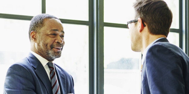 Two businessmen standing shaking hands at lunch meeting in restaurant