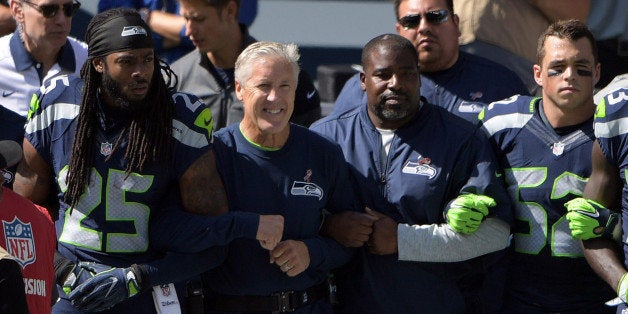 Sep 11, 2016; Seattle, WA, USA; Seattle Seahawks head coach Pete Carroll and cornerback Richard Sherman (25) interlock elbows with players and coaches during the playing of the national anthem during a NFL game against the Miami Dolphins at CenturyLink Field. Mandatory Credit: Kirby Lee-USA TODAY Sports