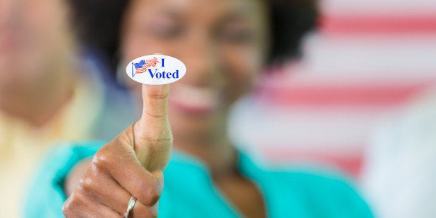 Smiling african american woman with an 'I voted' sticker on her thumb.