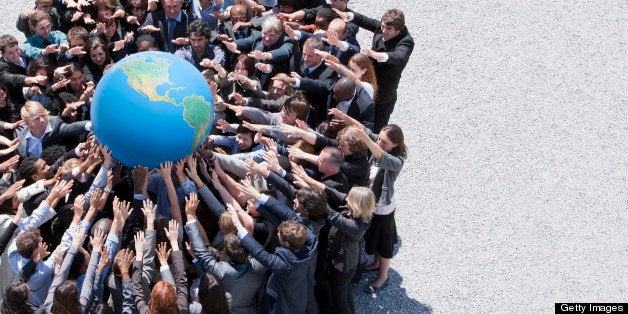 Crowd of business people in huddle reaching for globe