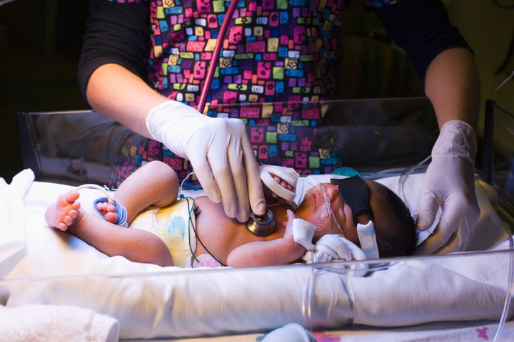 Nurse listening to baby girl's heartbeat in hospital
