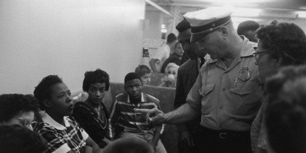 1958: A Caucasian policeman speaks with African-American protesters during a sit-in at Brown's Basement Luncheonette, Oklahoma. (Photo by Shel Hershorn/Hulton Archive/Getty Images)