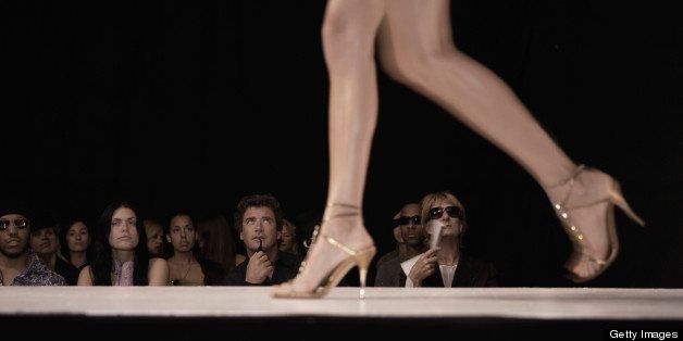 Female model walking on catwalk, invited guests watching