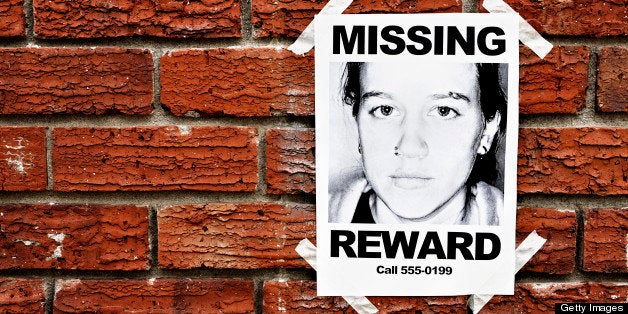 A 'Missing' poster of a teenage girl, offering a reward, is taped to a red brick wall, possibly in a police station. The phone number is a '555' dummy following the Hollywood convention. Please see http://en.wikipedia.org/wiki/555_%28telephone_number%29