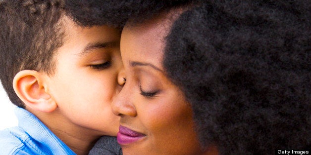 A young boy kisses his Mom on the cheek.