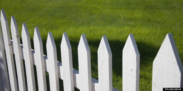 white picket fence with green...