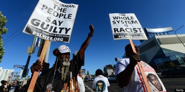 People hold placards and shout slogans during a rally at Leinert Park Los Angeles in the aftermath of George Zimmerman's acqu