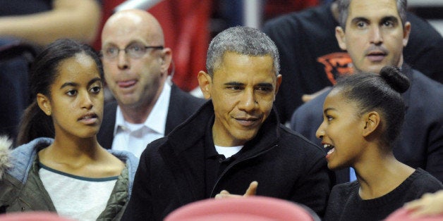 COLLEGE PARK, MD - NOVEMBER 17: US President Barack Obama with his daughters Malia (L) and Sasha (R) in their seats before a college basketball game between the Oregon State Beavers and the Maryland Terrapins on November 17, 2013 at the Comcast Center in College Park, Maryland. (Photo by Mitchell Layton/Getty Images)