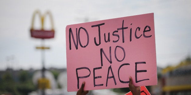 FERGUSON, MO - AUGUST 19: Demonstrators protest the killing of teenager Michael Brown on August 19, 2014 in Ferguson, Missouri. Brown was shot and killed by a Ferguson police officer on August 9. Despite the Brown family's continued call for peaceful demonstrations, violent protests have erupted nearly every night in Ferguson since his death. (Photo by Scott Olson/Getty Images)