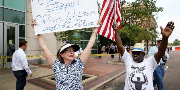CLAYTON, MO - AUGUST 20: Patty Canter (L) holds a sign reading, ' My Family & Friends Support Officer Wilson and the Police', as she walks next to Chris Finch who joined others in front of the Buzz Westfall Justice Center asking for justice for the Michael Brown family including the arrest of Darren Wilson the officer who shot him on August 20, 2014 in Clayton, Missouri. A grand jury will begin looking at the circumstances surrounding the fatal police shooting of an unarmed teenager Michael Brown who was shot and killed by a Ferguson, Missouri police officer on August 9. Despite the Brown family's continued call for peaceful demonstrations, violent protests have erupted nearly every night in Ferguson since his death. (Photo by Joe Raedle/Getty Images)