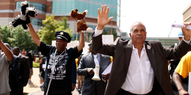 CLAYTON, MO - AUGUST 21: Anthony Shahid (L) and Zaki Baruti walk with other demonstrators through the street near the Buzz Westfall Justice Center where a grand jury will begin looking at the circumstances surrounding the fatal police shooting of an unarmed teenager Michael Brown on August 21, 2014 in Clayton, Missouri. The protesters are asking that justice be brought against the police officer that shot Brown on August 9. (Photo by Joe Raedle/Getty Images)