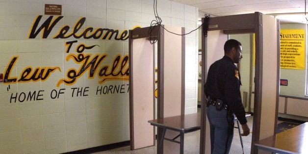 387319 02: Police Officer Jeff Tatum passes through a metal detector at Lew Wallace High School March 30, 2001 in Gary, IN af